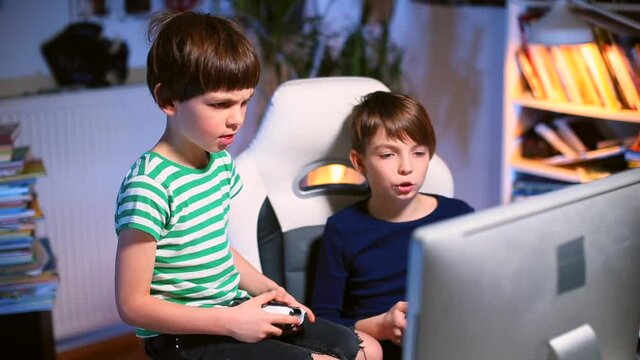 Two teenage boys focus of attention in the monitor, joysticks control hands. Video games ps4 at leisure at home in the evening. Camera movement.