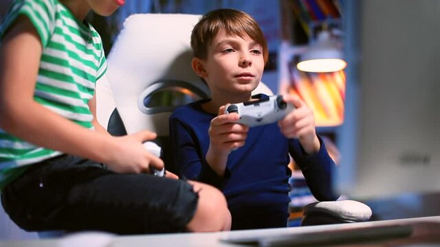 Preparing to start a video game ps4. The boy takes a joystick in his hand and starts playing. He looks at the monitor with his eyes. Camera movement.