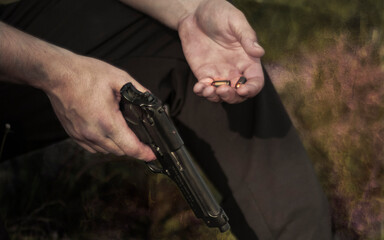 Pistol with cartridges in hands. Male two hands and a pistol. Cartridges close-up in hand
