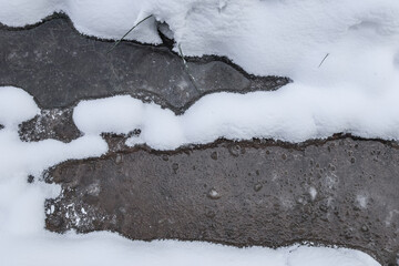 Fototapeta premium Frozen puddles in the snow. Two frozen puddles in the snow in the forest, close-up top view.