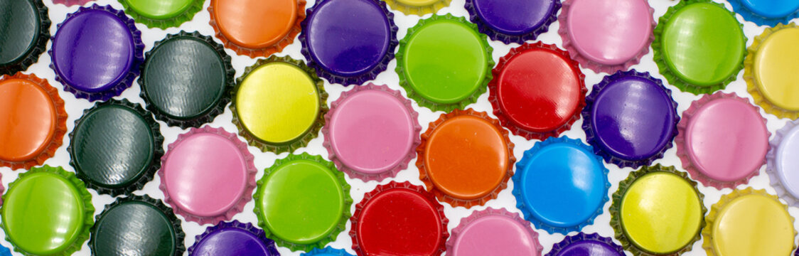 Wide background of colorful crown corks and caps in the colors blue, red, orange, grey and gold, photoraphed from above