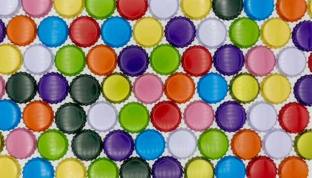 Crown corks and caps in various colors, such as blue, red, orange and gold. Lined up as a colorful background