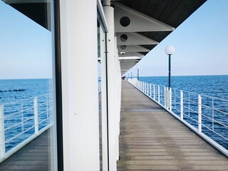 Covered Boardwalk On Sea Against Blue Sky