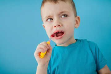 Little cute boy brushing his teeth on blue background