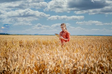 Woman caucasian technologist agronomist with tablet computer in the field of wheat checking quality and growth of crops for agriculture. Agriculture and harvesting concept