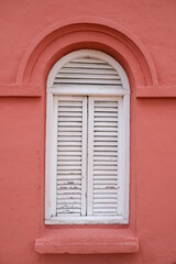 Fototapeta na wymiar Old white wooden window on a red building.