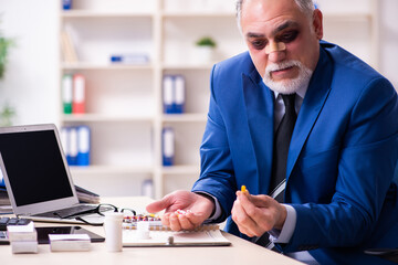 Old face injured employee sitting in the office