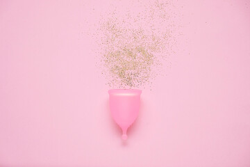 Menstrual cup with glitter on pink background. Alternative feminine hygiene product during the period. Women health concept