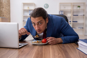 Hungry male employee eating buckwheat during break