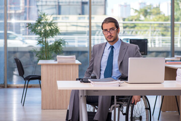 Fototapeta na wymiar Young male employee in wheel-chair working in the office