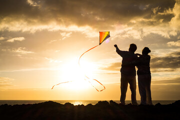 close up and portrait of two old and mature people playing and enjoying with a flaying kite at the...