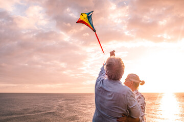 close up and portrait of two old and mature people playing and enjoying with a flaying kite at the...