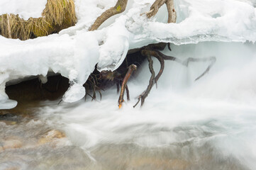 Mountain river among stones and snow.