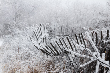 a wooden fence covered with snow. in the background, the snow flakes are falling in a gloomy night