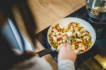 Top view on cooking pan with chicken meat and vegetables - unknown woman making healthy meal at...