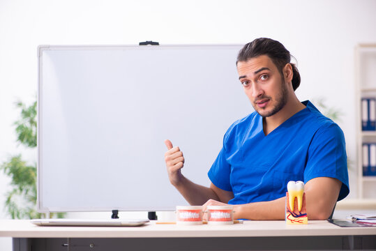 Young male doctor teacher dentist in front of whiteboard