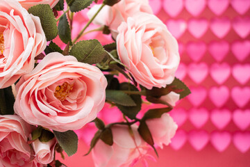 Close up of a bouquet of pink roses on pink and red hearts background. Valentine's Day decoration