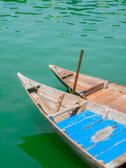 Pair of traditional wooden Vietnamese sampan rowboats on calm water
