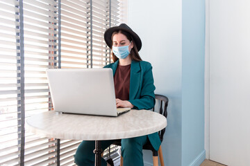 Young woman in suite with protective mask is working on computer.