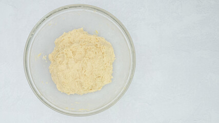 Pizza dough or bread dough in a glass bowl, view from above, copy space