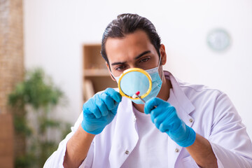 Young male chemist working in the lab during pandemic