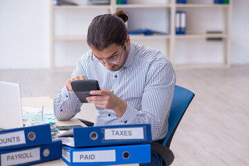Young male bookkeeper calculating tax payments in the office
