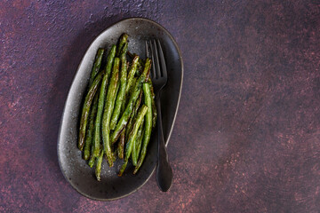 Freshly roasted whole green beans on a serving platter, with a rustic background
