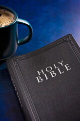 Holy Bible on a Dark Blue Surface with a Cup of Hot Coffee