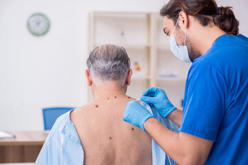 Fototapeta premium Old man visiting young male doctor dermatologist