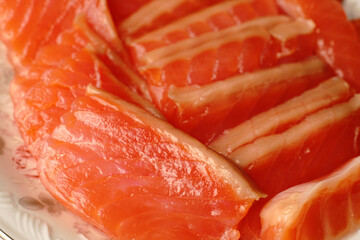 The pieces of red fish on the plate are evenly sliced.