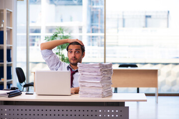 Young male employee unhappy with excessive work in the office