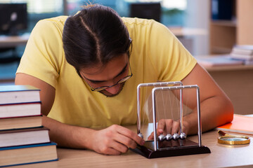 Young male student physicist preparing for exams in the classroom