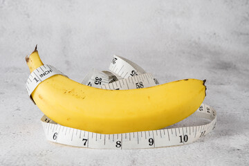 Banana with measuring tape on white grunge backdrop - suitable for health care and diet conceptual...