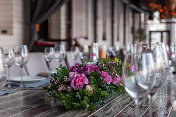 Modern veranda restaurant interior, flowers, banquet setting, glasses, plates