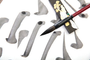 Brush strokes on white paper, a brush and an ink bar