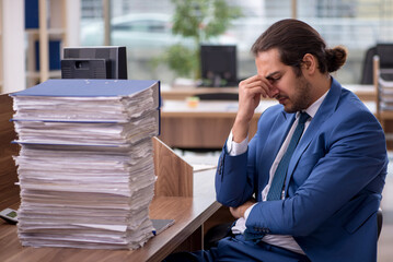 Young male employee unhappy with excessive work in the office