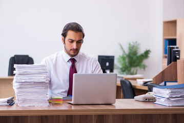 Fototapeta na wymiar Young male employee unhappy with excessive work in the office