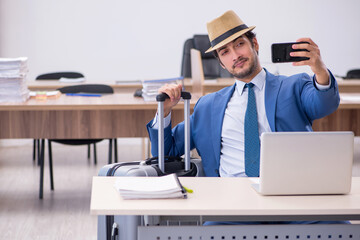 Young male employee preparing for trip in the office