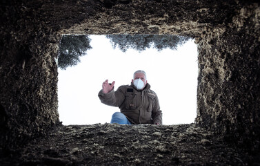 Ein Mann mit Schutzmaske steht über einem offenen Grab