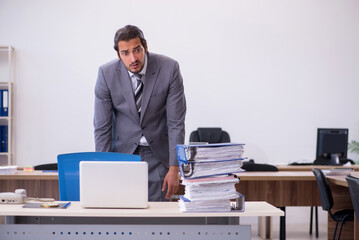 Young male employee unhappy with excessive work in the office