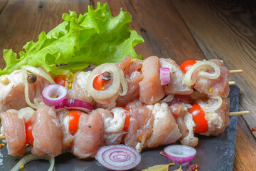 Raw pieces of pork shish kebab in marinade with pepper, onion,bay leaf.Pork shish kebab, ready to cook, barbecue, on an old wooden table.Rustic style.Selective focus.