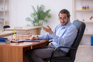 Young male teacher physicist in the classroom