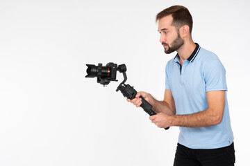 Videographer on a light background. Man holds a camera on stabilizer. Concept - shooting video with professional camera. Videographer career. Video filming services. Professional shooting equipment.