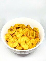 Banana chips are crunchy and tasty, being served in a medium sized bowl, to eat.
