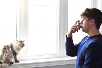 Young man using puffer inhaler to control his asthma caused by pet allergies