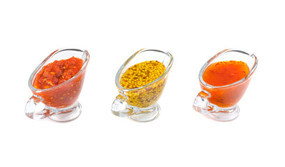 Red delicious ketchup or tomato sauce, adjika and mustard with grains in three clear glass saucepan...