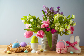 Easter holiday concept with Easter eggs and beautiful tulip flowers bouquet on wooden table