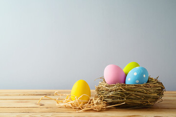Easter holiday background with easter eggs in bird nest on wooden table
