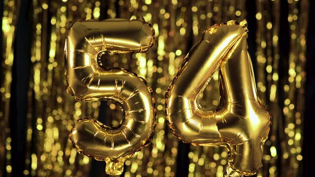 The golden number 54 fifty four is made from an inflatable balloon on a yellow background. One of the complete set of numbers. Birthday, anniversary, date concept