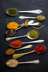 Various spices spoons on black table. Top view with copy space